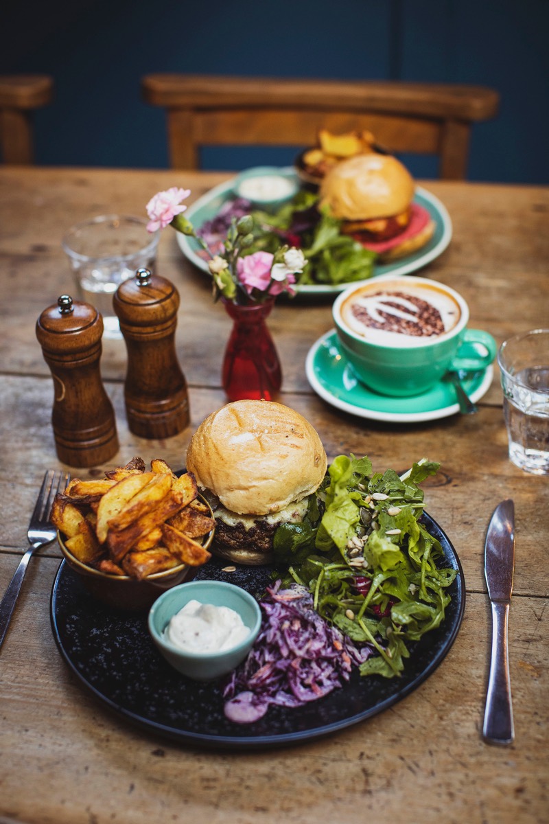 A burger with hand cut chips, slaw and salad on the table at The Warren
